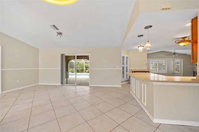 empty room with ceiling fan, light tile patterned floors, vaulted ceiling, and a wealth of natural light