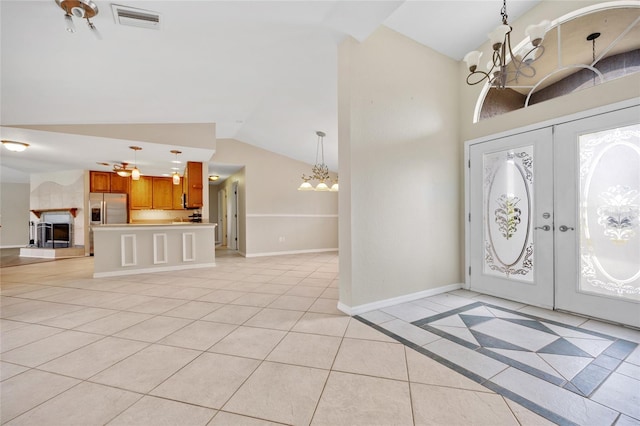 entrance foyer featuring an inviting chandelier, lofted ceiling, french doors, and light tile patterned floors