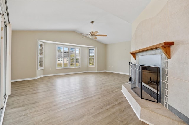 living room featuring vaulted ceiling, ceiling fan, a fireplace, and light hardwood / wood-style flooring