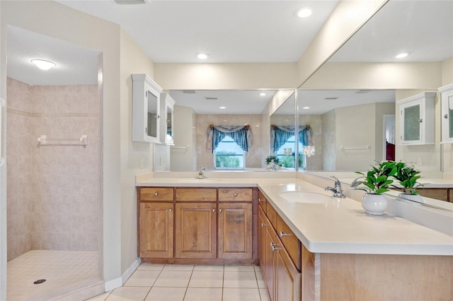 bathroom featuring tile patterned flooring, vanity, and tiled shower