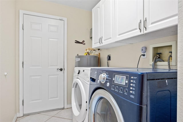 washroom featuring independent washer and dryer, cabinets, water heater, and light tile patterned floors