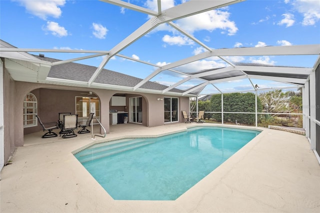 view of swimming pool featuring ceiling fan, glass enclosure, and a patio area