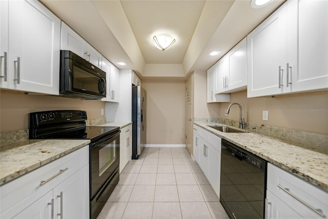 kitchen featuring light stone countertops, white cabinets, black appliances, sink, and light tile patterned floors