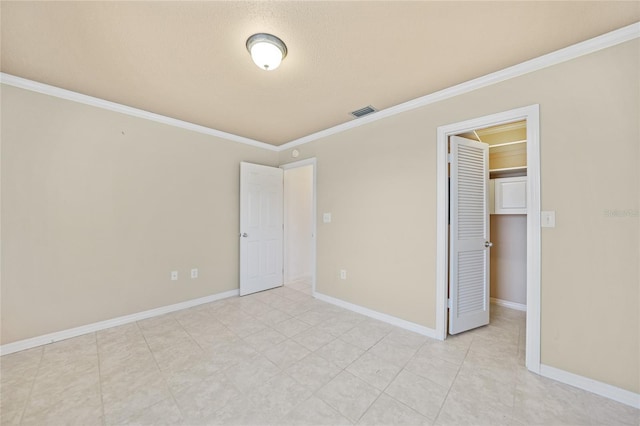 unfurnished bedroom with a spacious closet, a closet, and crown molding