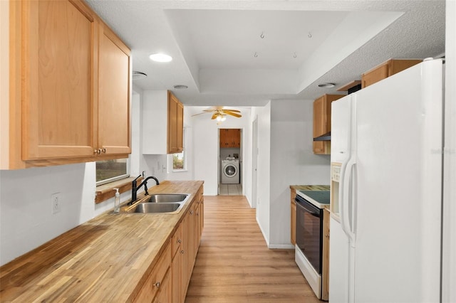 kitchen with white appliances, washer / clothes dryer, a tray ceiling, sink, and light brown cabinets