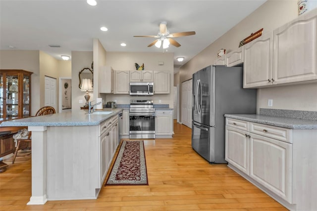 kitchen featuring sink, light hardwood / wood-style flooring, ceiling fan, stainless steel appliances, and white cabinets