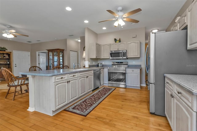 kitchen featuring appliances with stainless steel finishes, sink, light hardwood / wood-style flooring, and kitchen peninsula