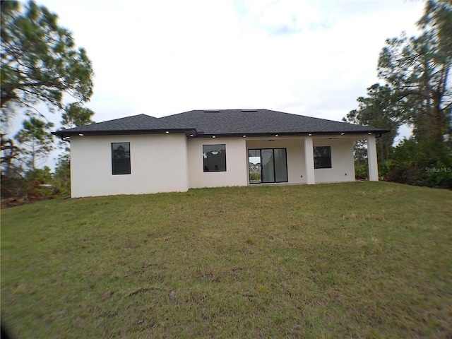 back of property with ceiling fan and a yard