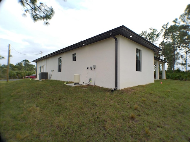 view of side of property with central AC and a yard