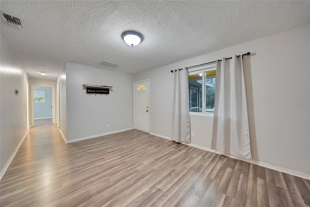 unfurnished room featuring light hardwood / wood-style flooring and a textured ceiling