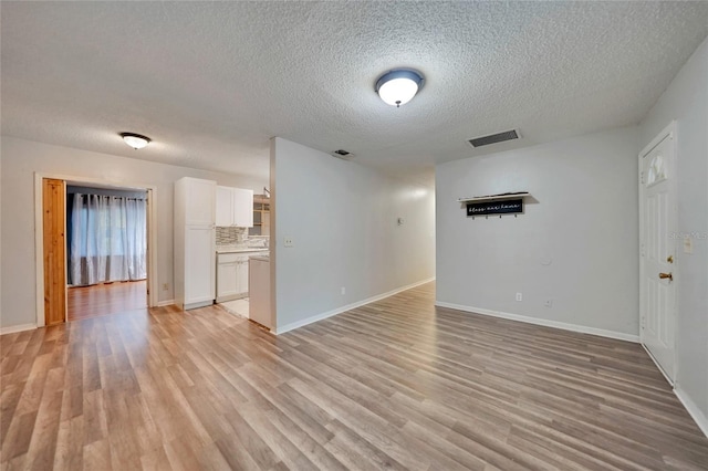 unfurnished living room featuring a textured ceiling and light wood-type flooring