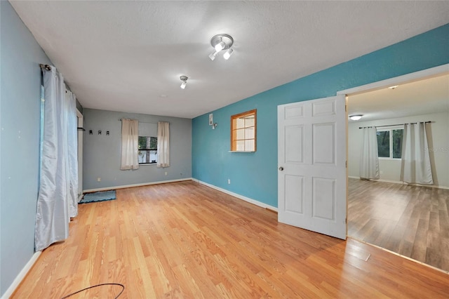 empty room with light hardwood / wood-style floors and a textured ceiling