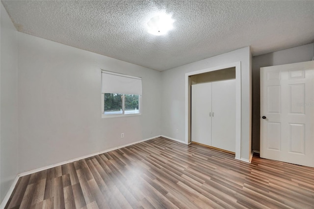 unfurnished bedroom featuring hardwood / wood-style flooring, a closet, and a textured ceiling