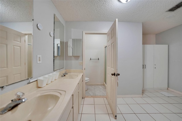 bathroom with vanity, a textured ceiling, tile patterned floors, and toilet