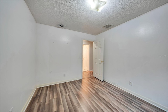 empty room with light hardwood / wood-style floors and a textured ceiling