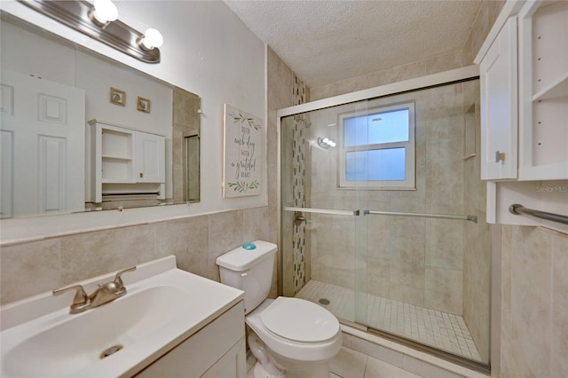 bathroom featuring tile walls, vanity, a shower with door, and a textured ceiling