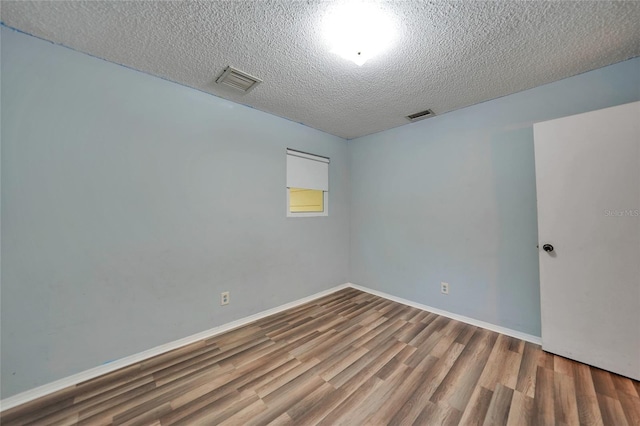 spare room with hardwood / wood-style flooring and a textured ceiling