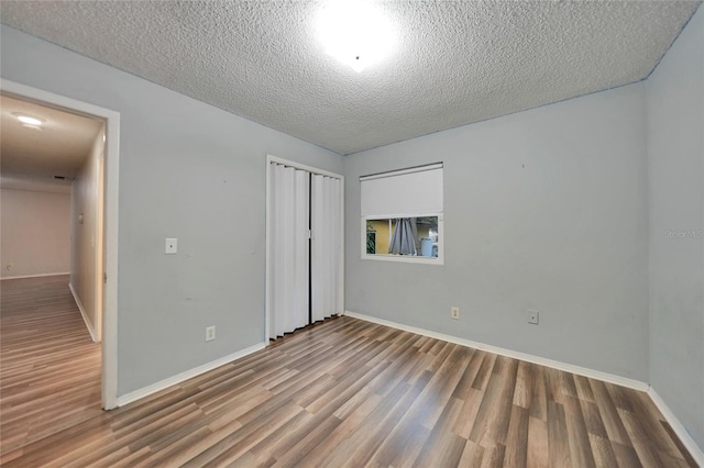 unfurnished bedroom with wood-type flooring, a closet, and a textured ceiling