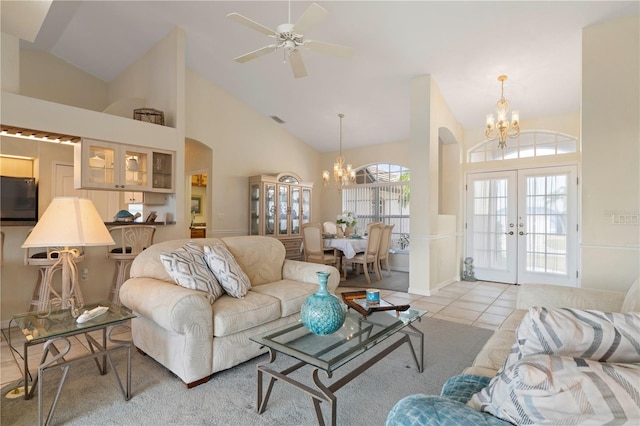 tiled living room with ceiling fan with notable chandelier, french doors, and high vaulted ceiling