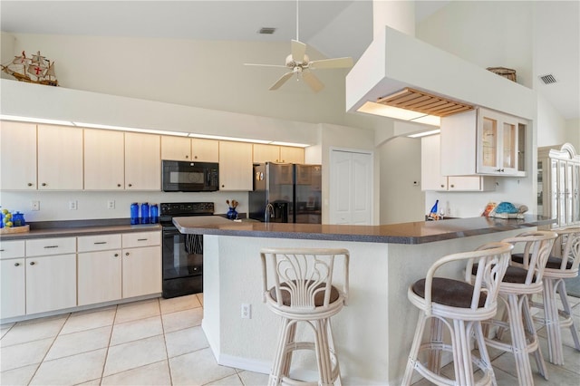 kitchen featuring kitchen peninsula, ceiling fan, light tile patterned floors, a kitchen bar, and black appliances