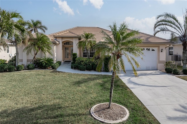 mediterranean / spanish-style home featuring a garage, cooling unit, and a front yard