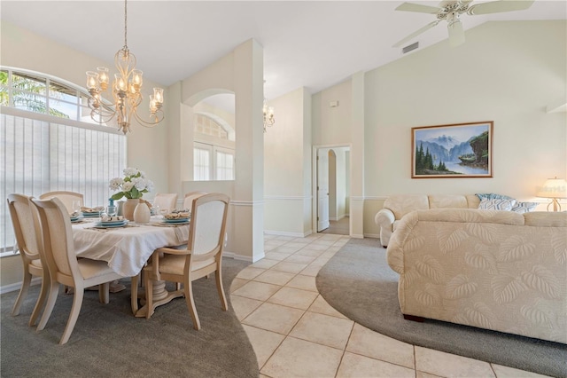 tiled dining area featuring ceiling fan with notable chandelier and lofted ceiling