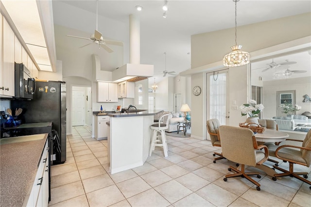 kitchen featuring light tile patterned floors, a kitchen bar, white cabinetry, and a high ceiling