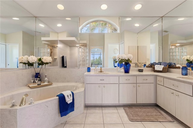 bathroom with tiled bath, vanity, lofted ceiling, and tile patterned flooring