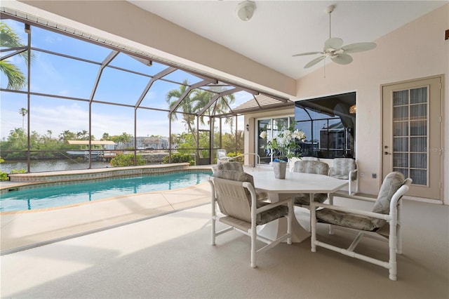 view of swimming pool with glass enclosure, a patio area, a water view, and ceiling fan