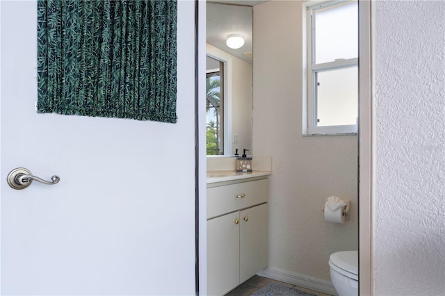 bathroom with toilet, vanity, and a healthy amount of sunlight