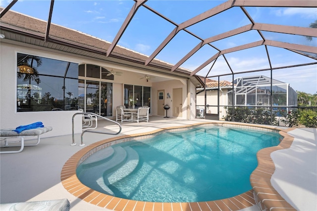 view of pool with a patio, glass enclosure, and ceiling fan