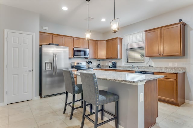 kitchen featuring light stone countertops, a center island, decorative light fixtures, stainless steel appliances, and a kitchen breakfast bar