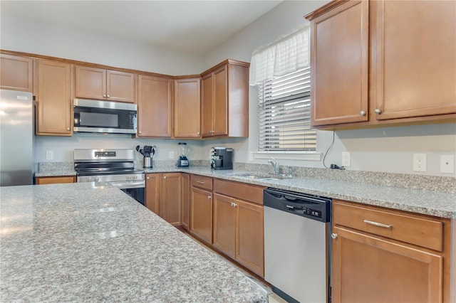 kitchen with sink, stainless steel appliances, and light stone countertops