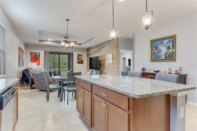 kitchen featuring a kitchen island, hanging light fixtures, a raised ceiling, light stone counters, and stainless steel dishwasher