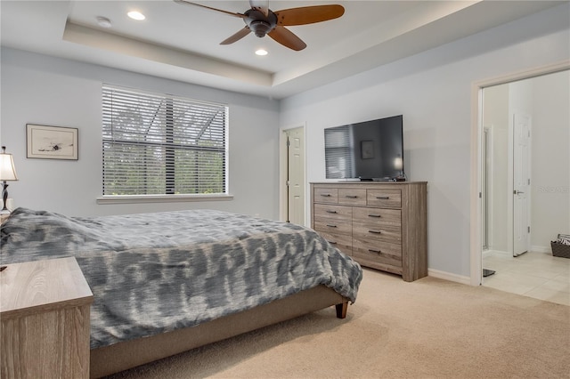 carpeted bedroom with ceiling fan and a raised ceiling