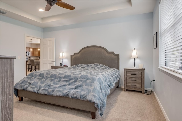 bedroom with ceiling fan, a raised ceiling, and light carpet