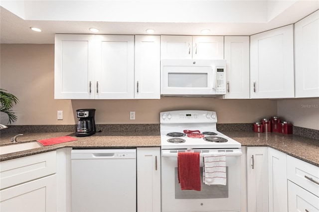 kitchen featuring sink, white appliances, white cabinetry, and dark stone countertops