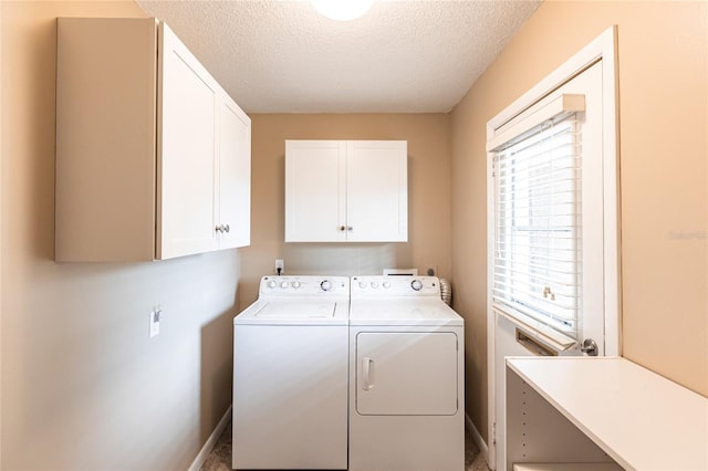 clothes washing area featuring separate washer and dryer, a textured ceiling, and cabinets