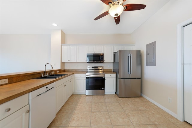 kitchen with light tile patterned flooring, appliances with stainless steel finishes, sink, and white cabinets