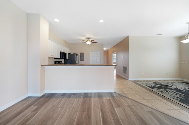 kitchen with stainless steel refrigerator, white cabinetry, kitchen peninsula, and light hardwood / wood-style flooring