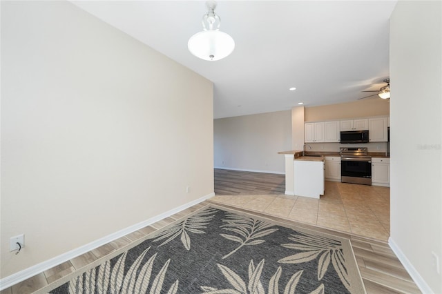 kitchen with butcher block countertops, sink, light tile patterned floors, white cabinets, and stainless steel range with electric cooktop