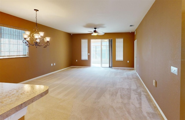 unfurnished living room featuring carpet and ceiling fan with notable chandelier