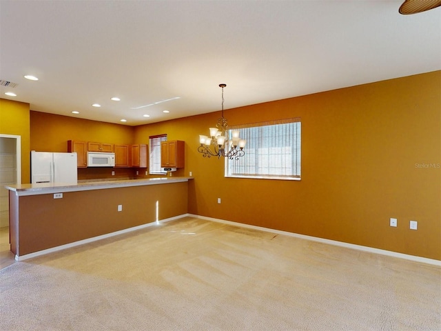 kitchen with an inviting chandelier, decorative light fixtures, light carpet, kitchen peninsula, and white appliances