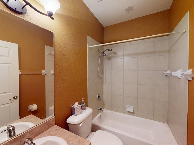 full bathroom with tiled shower / bath, vanity, and toilet