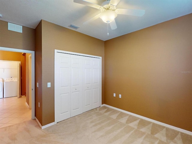 unfurnished bedroom with a closet, light colored carpet, independent washer and dryer, and ceiling fan