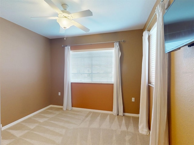 carpeted spare room featuring a healthy amount of sunlight and ceiling fan