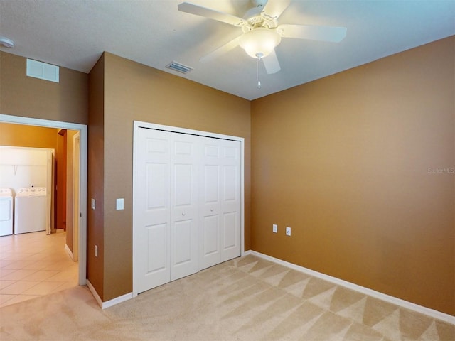 unfurnished bedroom with washing machine and dryer, light colored carpet, ceiling fan, and a closet