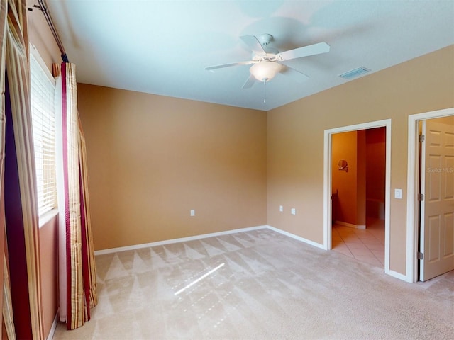 unfurnished bedroom with ceiling fan, ensuite bath, and light carpet