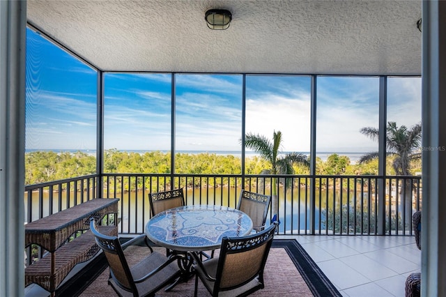 sunroom featuring a water view