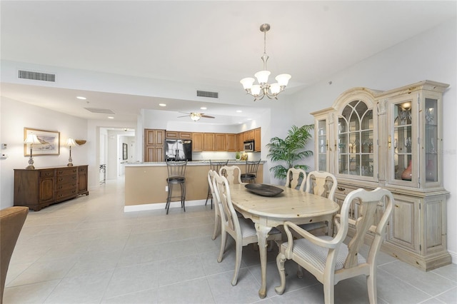 tiled dining room with ceiling fan with notable chandelier